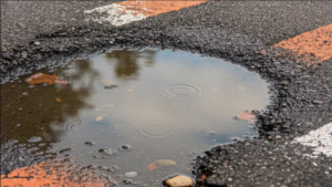 Close up of asphalt pothole filled with water after rain
