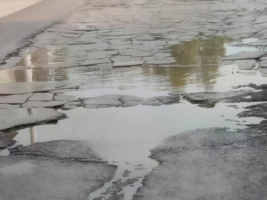 Rain damaged asphalt road showing cracks and surface failure